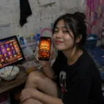 ภาพผู้เล่นถือโทรศัพท์แสดงผล Mega Win พร้อมเกมสล็อตบนหน้าจอคอมพิวเตอร์ ใช้ประกอบบทความแนะนำเกมสล็อต TB68 และแนวทางการเล่นปี 2026